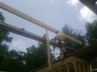 Carpenter setting a ridge beam over a new addition frame — Ice Dam Removal by Roofing Brothers in Baxley