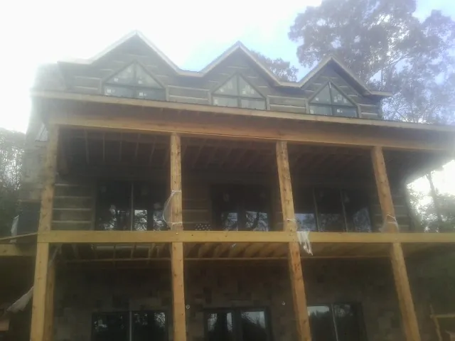 Dormers and porch framing on a large log home under construction — Roof Coating work by our crew in Baxley