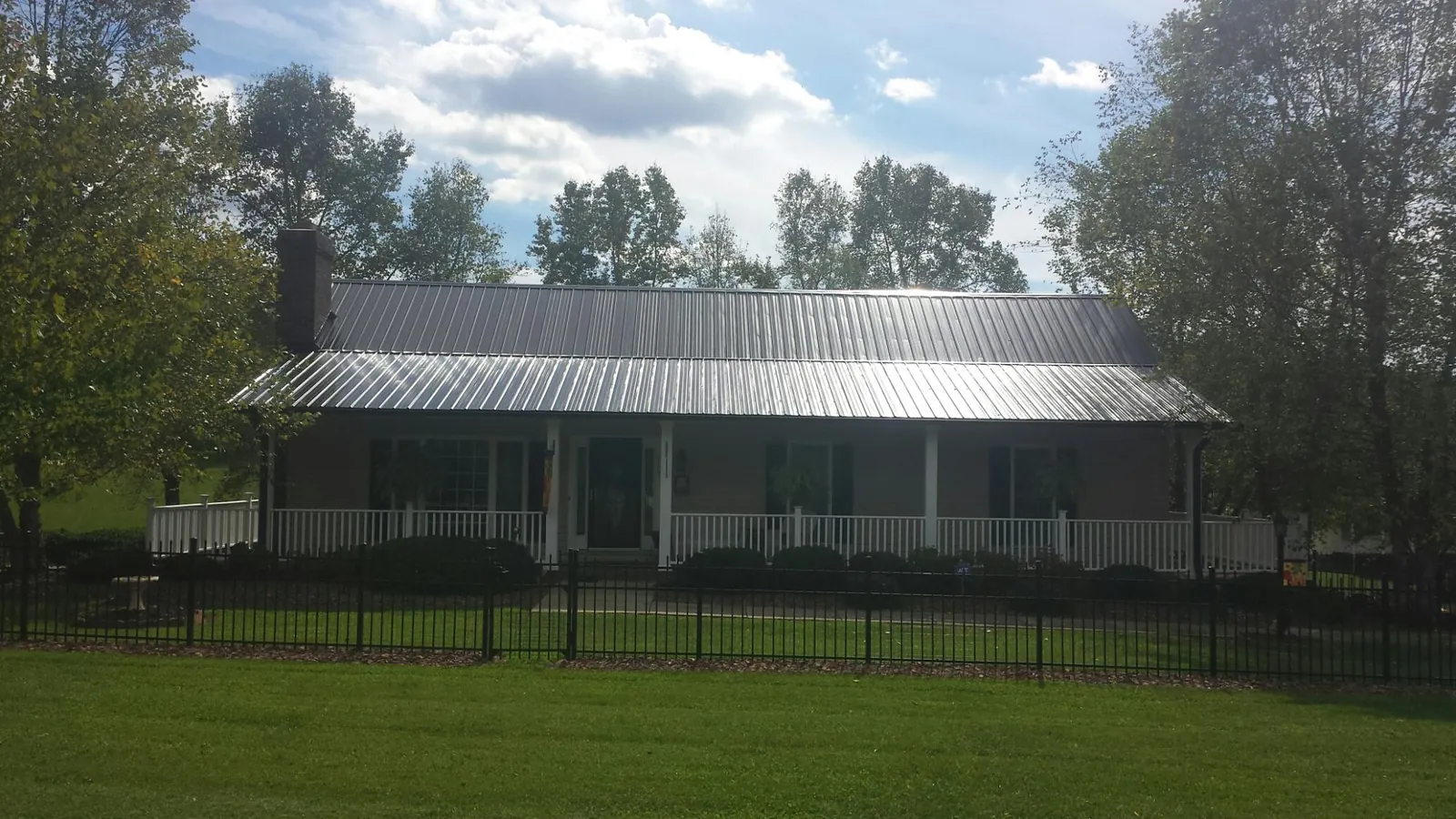 Gray metal roof on a brick ranch with a full width front porch — Gutter Guard Installation work by our crew in Baxley