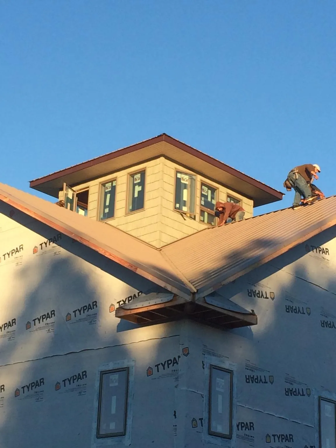 Roofers working around a rooftop cupola on a new metal roof at sunset — Roof Waterproofing in Baxley by Roofing Brothers